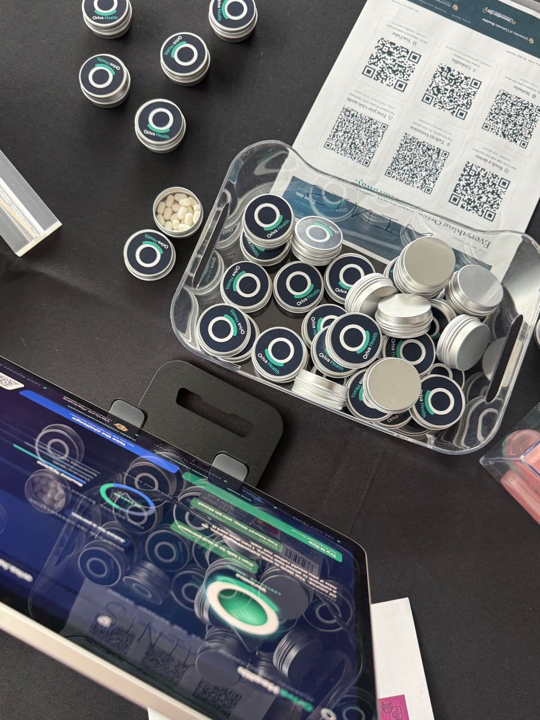 Oriva Health mint tins and the QR code sheet on the booth table