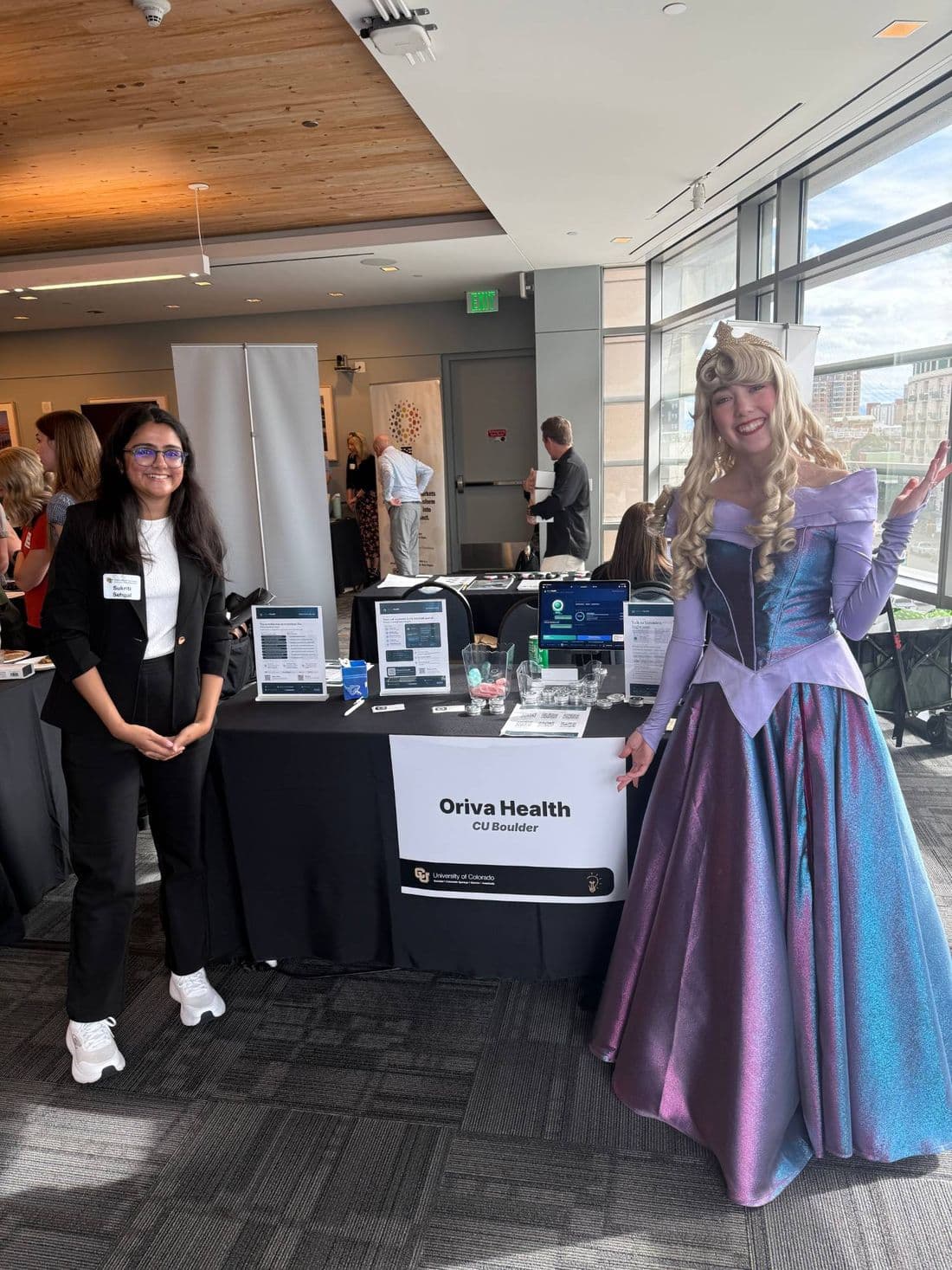 Sukriti Sehgal at the Oriva Health booth with a costumed princess visitor